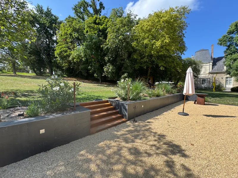Parc aménagé avec muret en corten, escalier et terrasse en gravier